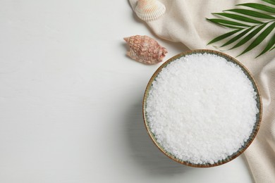Photo of Bowl of natural sea salt, shell and leaf on white wooden table, flat lay. Space for text