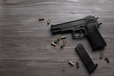 Pistol and bullets on wooden table, flat lay with space for text. Professional gun