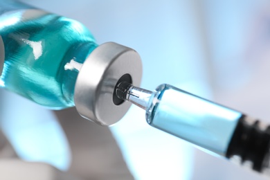 Filling syringe with vaccine from vial, closeup