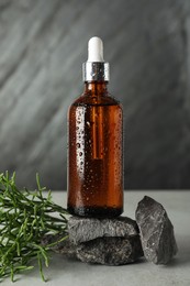 Bottle of hydrophilic oil, rocks and green plant on light grey table