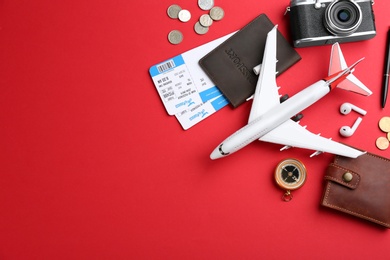 Flat lay composition with toy airplane and travel items on red background. Space for text