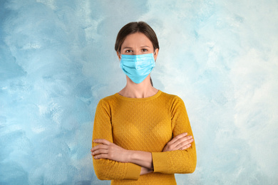 Woman with disposable mask on face against light blue background