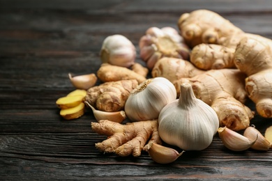 Photo of Ginger and garlic on black wooden table, space for text. Natural cold remedies