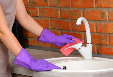 Photo of Woman cleaning sink with rag in kitchen, closeup