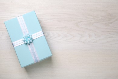 Light blue gift box on white wooden table, top view. Space for text