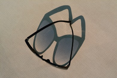 Photo of Stylish sunglasses on grey surface. Beach accessory, top view