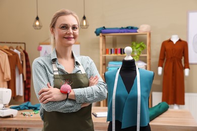 Portrait of dressmaker near mannequin in workshop