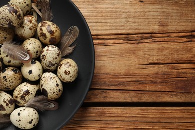 Photo of Plate with quail eggs on wooden table, top view. Space for text