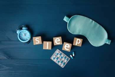Word Sleep, alarm clock, pills and mask on blue wooden table, flat lay. Insomnia treatment