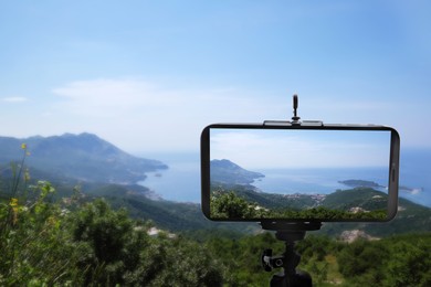 Taking photo of beautiful mountain landscape with smartphone mounted on tripod