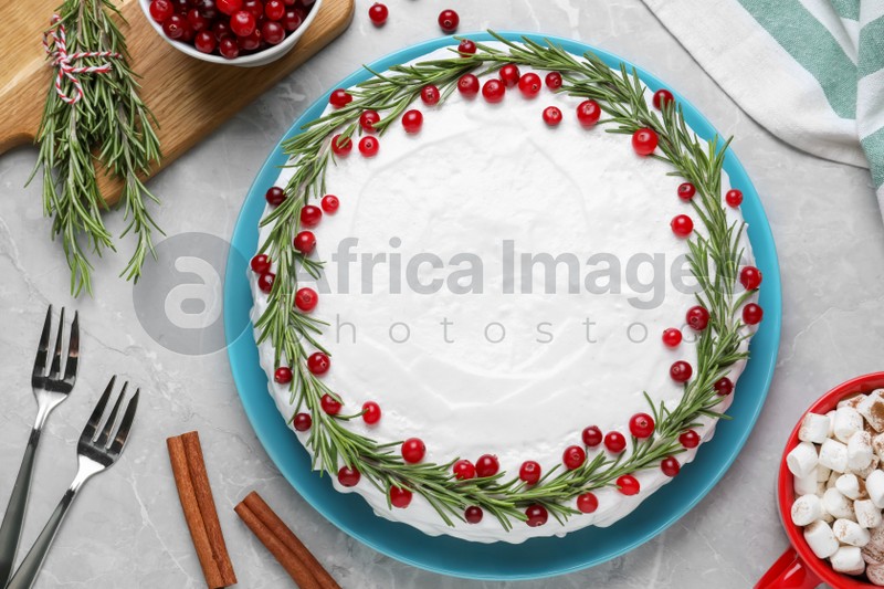 Photo of Traditional Christmas cake decorated with rosemary and cranberries on light grey marble table, flat lay