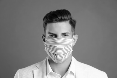 Man wearing medical face mask on grey background. Black and white photography
