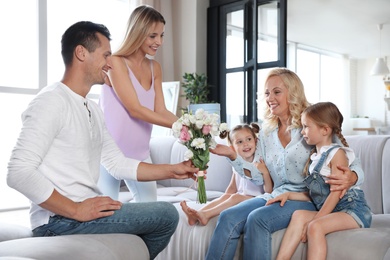 Happy family with little children congratulating mature woman in living room