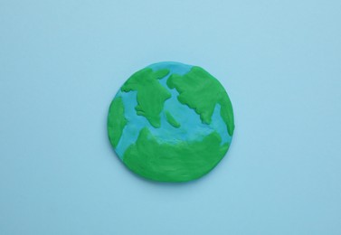 Plasticine model of planet on light blue background, top view. Earth Day
