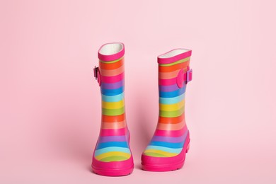 Pair of striped rubber boots on pink background