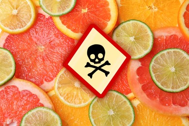 Skull and crossbones sign on different fresh citrus fruits, top view. Be careful - toxic