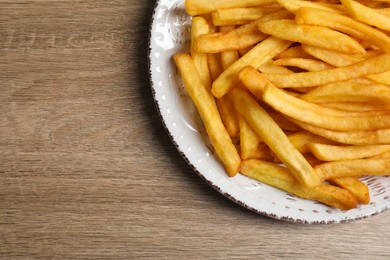 Photo of Tasty french fries on wooden table, top view. Space for text