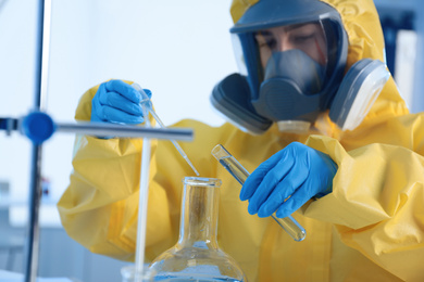 Scientist in chemical protective suit working at laboratory, focus on hands. Virus research
