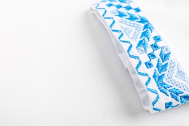 Photo of Beautiful white shirt with light blue Ukrainian national embroidery, closeup. Space for text