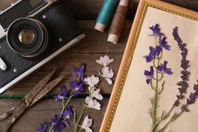 Photo of Flat lay composition with beautiful dried flowers, vintage camera and photo frame on wooden table