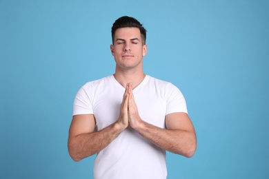 Man meditating on light blue background. Stress relief exercise