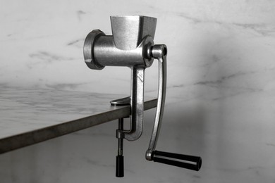 Photo of Metal manual meat grinder on table against white marble background