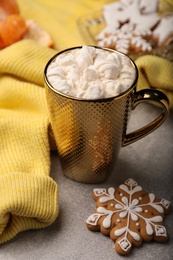 Photo of Composition with delicious marshmallow drink and yellow sweater on light grey table