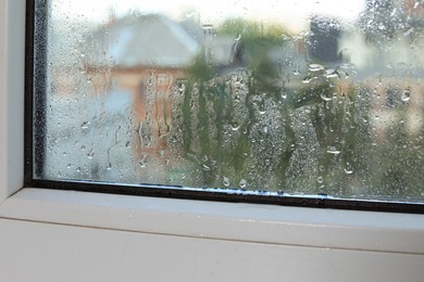 Wet window on rainy day, closeup. View from inside
