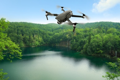 Modern drone flying over picturesque lake near mountains. Aerial survey