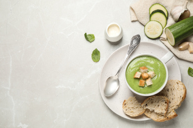 Tasty homemade zucchini cream soup served on light table, flat lay. Space for text