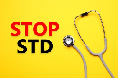 Image of Text STOP STD and stethoscope on yellow background, top view