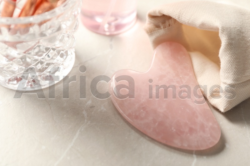 Photo of Rose quartz gua sha tool on light marble table
