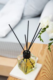 Reed diffuser on wooden nightstand in bedroom