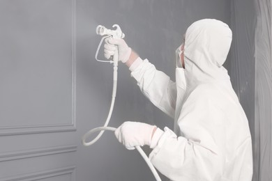 Photo of Decorator dyeing wall in grey color with spray paint