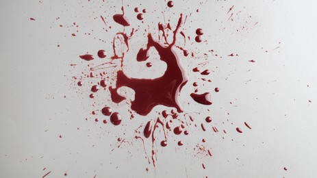 Stain and splashes of blood on light grey background, top view
