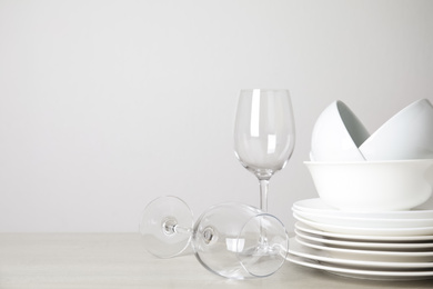 Clean plates, bowls and glasses on table against white background. Space for text