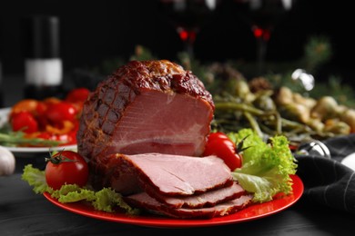 Plate with delicious ham, lettuce and tomatoes on black wooden table