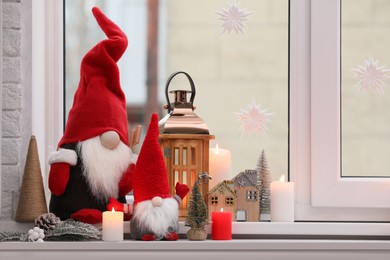 Cute Christmas gnomes and other festive decorations on windowsill in room, space for text