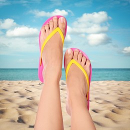 Woman wearing stylish flip flops resting on sandy beach and enjoying beautiful seascape, closeup 