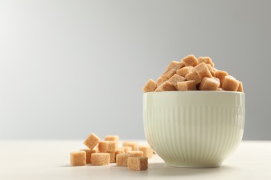 Brown sugar cubes on white table, space for text