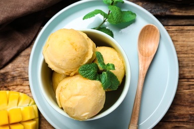 Delicious mango ice cream served on wooden table, flat lay