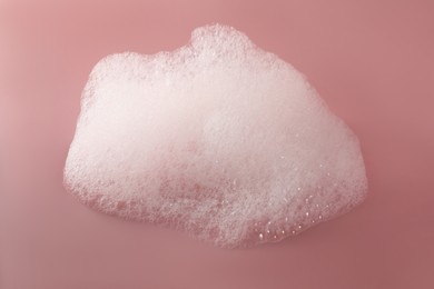 Fluffy bath foam on pink background, top view
