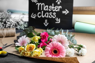Flower arrangement master class. Paper wrapping with flowers on table, closeup