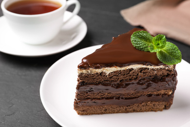 Delicious chocolate cake with mint on black table, closeup