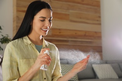 Woman applying spray sanitizer onto hand at home
