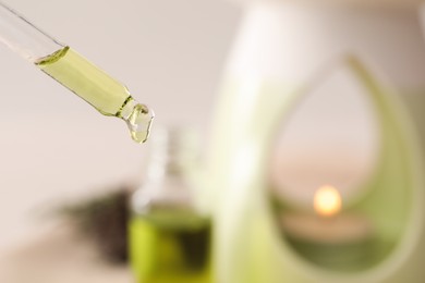 Pipette with coniferous essential oil for aroma lamp on blurred background, closeup
