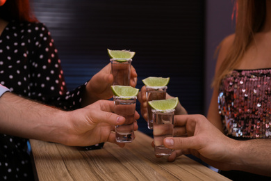Young people toasting with Mexican Tequila shots at bar, closeup