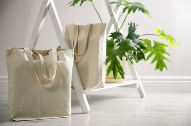 Eco bags and houseplant near white wall indoors. Space for design