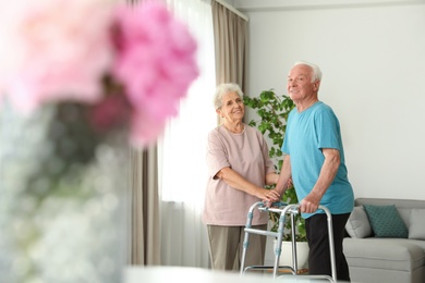 Elderly woman and her husband with walking frame indoors