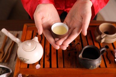 Master offering cup of freshly brewed tea during traditional ceremony at table, closeup